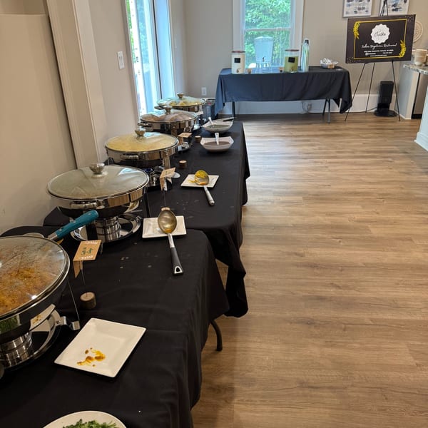 Chaska Indian vegetarian restaurant buffet setup with chafing dishes, serving utensils, and a welcome sign.