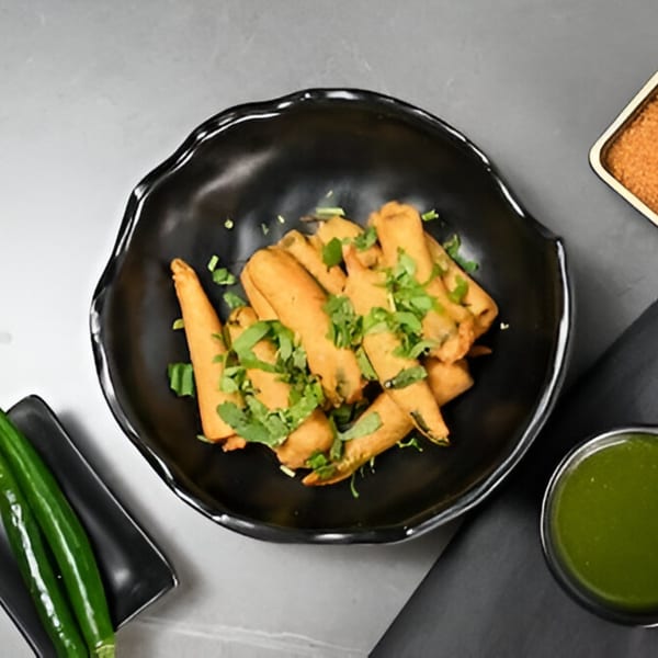 Chaska's crispy Indian spring rolls, garnished with fresh cilantro, served with green chutney and spices.