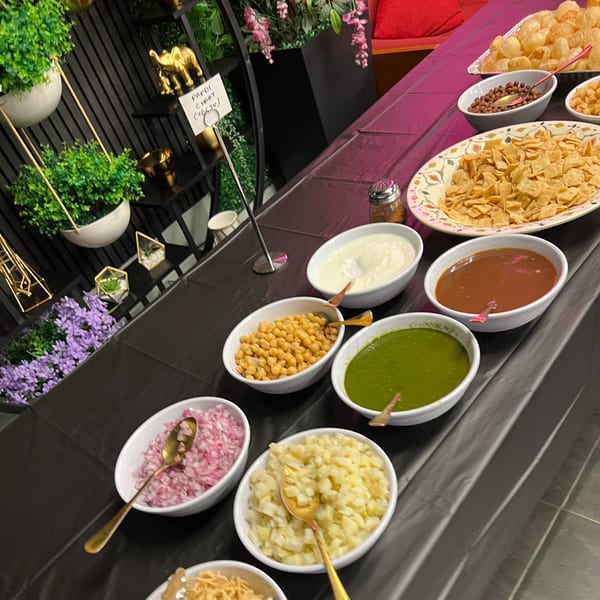 A Chaska Papdi Chaat bar with various toppings and sauces on a black table.